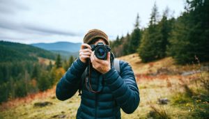 A beginner photographer adjusting camera settings in a scenic outdoor environment, symbolizing the learning journey of mastering aperture, shutter speed, and ISO.