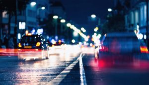 A vibrant city nightscape featuring glowing streetlights and light trails, demonstrating the techniques of low light photography with bokeh effects in the background.